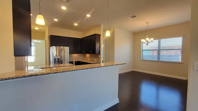 a large kitchen with stainless steel appliances a large counter top a stove and a refrigerator