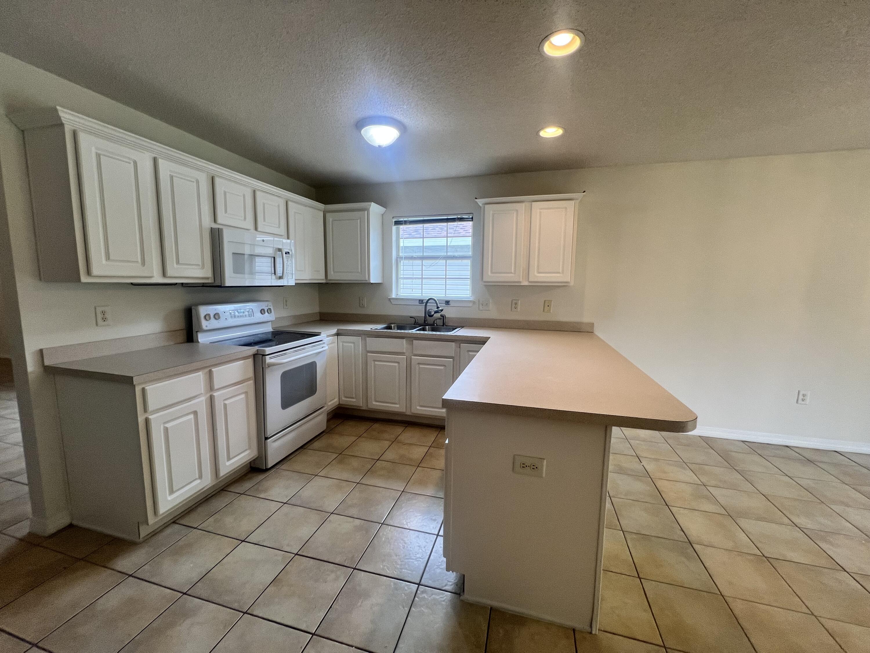 8 Howard Street Niceville, FL 32578 - Photo 14 of 22 a kitchen with a sink a stove cabinets and a window
