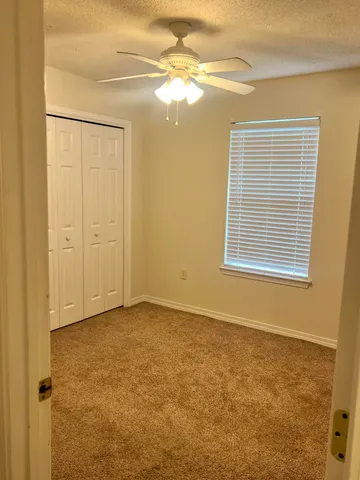 a view of an empty room with window and chandelier fan