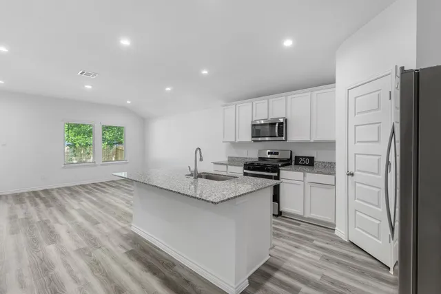 a kitchen with stainless steel appliances granite countertop a refrigerator sink and stove