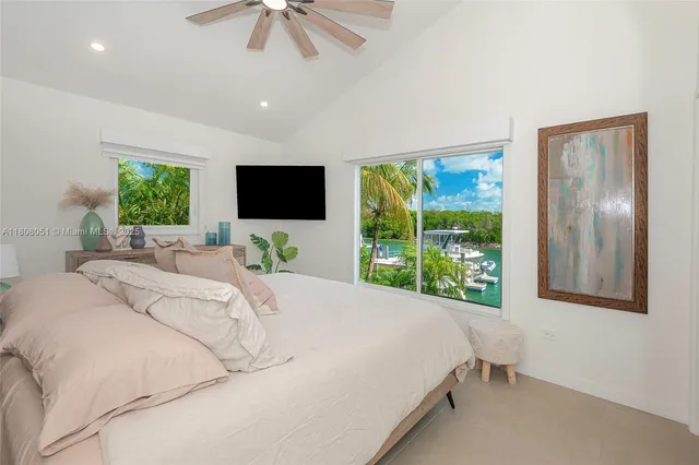 a bedroom with a bed and a flat tv screen next to a window