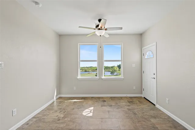 an empty room with windows and fan