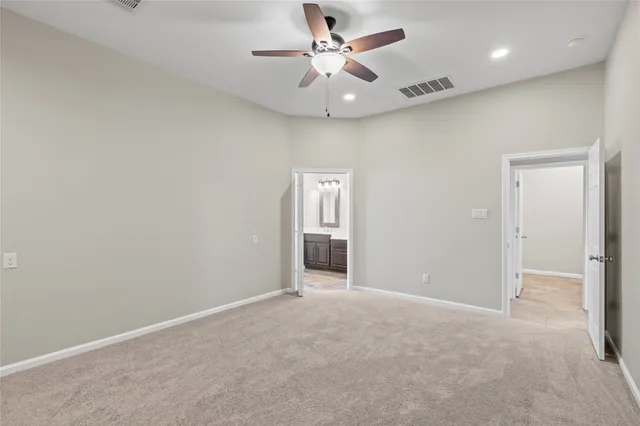 an empty room with chandelier fan and windows