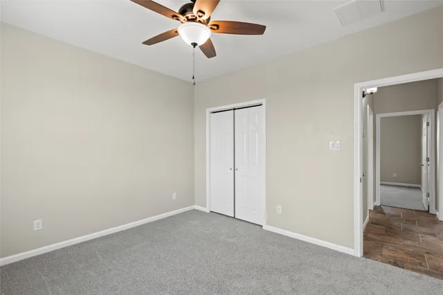 an empty room with a chandelier fan and a ceiling fan