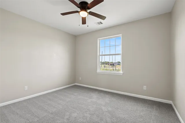 an empty room with a window and ceiling fan