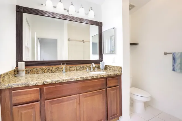 a bathroom with a granite countertop sink a toilet and a mirror