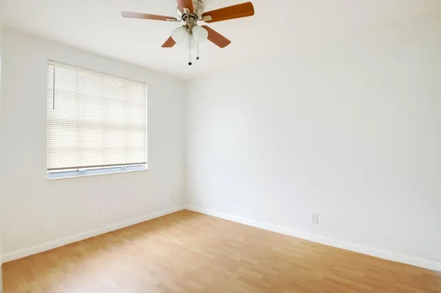 an empty room with a window and a fan