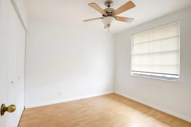 an empty room with a window and a fan