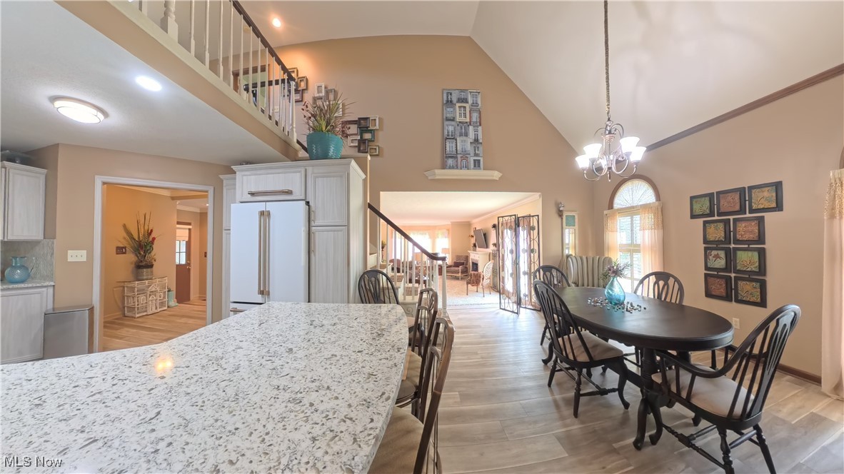 7017 Kirk Road Canfield, OH 44406 - Photo 11 of 35 Dining room featuring light wood-style flooring, high vaulted ceiling, stairway, and a chandelier