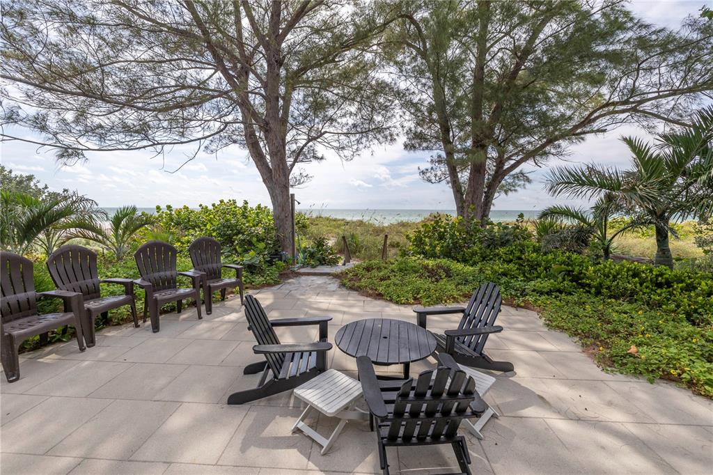 516 Gulf Boulevard Indian Rocks Beach, FL 33785 - Photo 54 of 97 a view of a patio with table and chairs potted plants and large tree