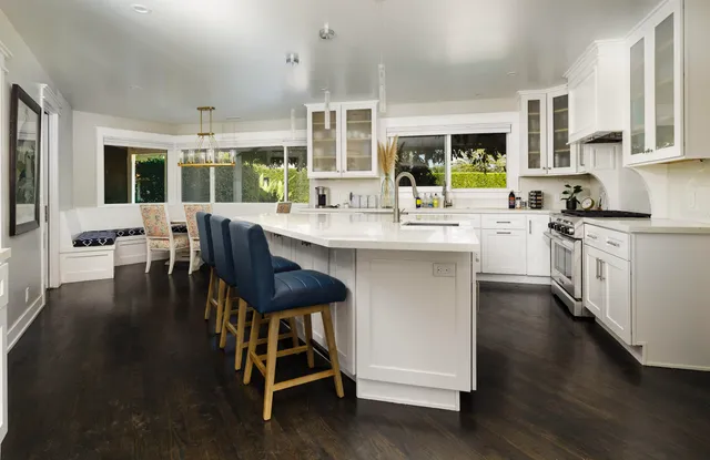 a kitchen with stainless steel appliances granite countertop a stove a refrigerator a kitchen island and chairs in it