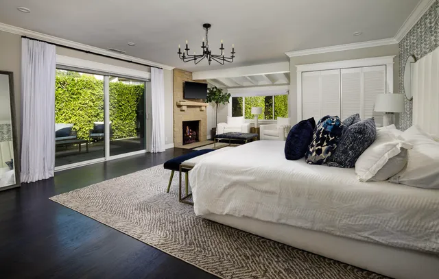 a bedroom with a bed balcony fireplace and a large window