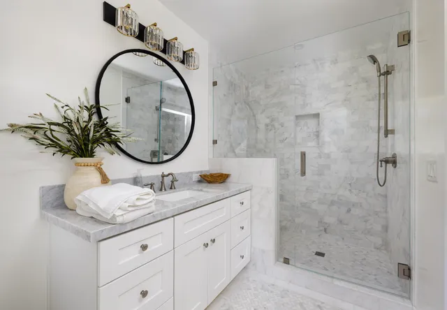 a bathroom with a granite countertop sink a mirror and a shower