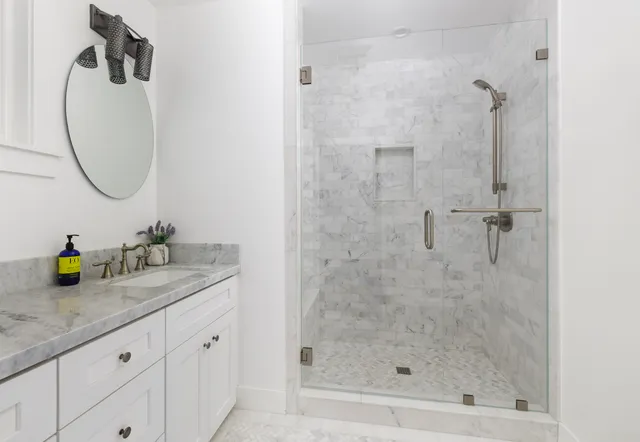 a bathroom with a granite countertop sink a mirror and a shower