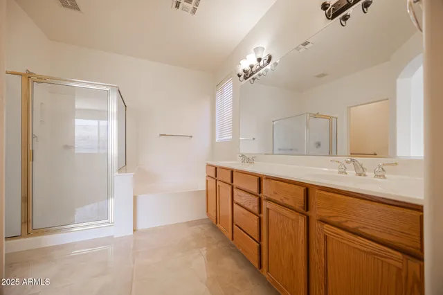 a spacious bathroom with double vanity a mirror and a shower