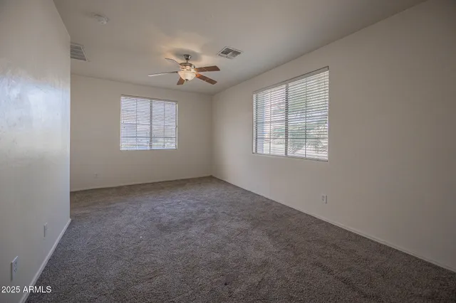 en empty room with windows and ceiling fan