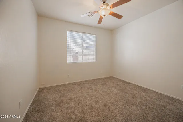 an empty room with windows and chandelier fan