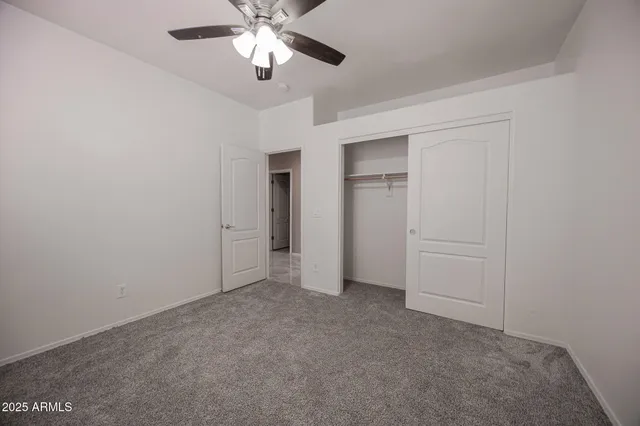 a view of an empty room and chandelier fan