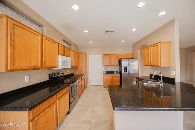 a kitchen with stainless steel appliances granite countertop a sink a stove and a refrigerator