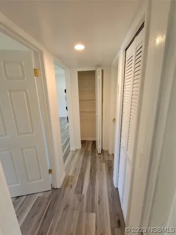 a view of a hallway with wooden floor and closet area