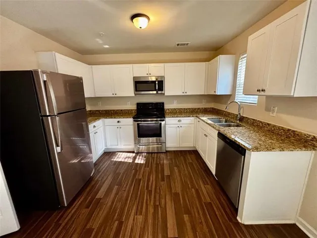 a kitchen with stainless steel appliances a refrigerator a sink a stove top oven a refrigerator and cabinets