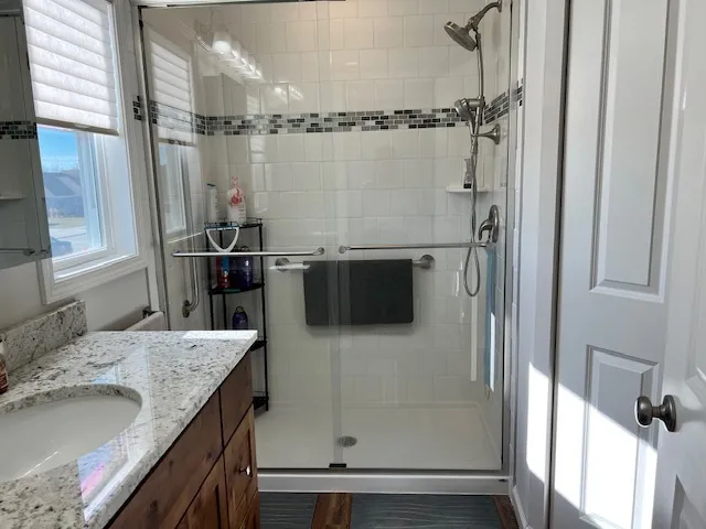 a bathroom with a granite countertop sink a mirror and a shower