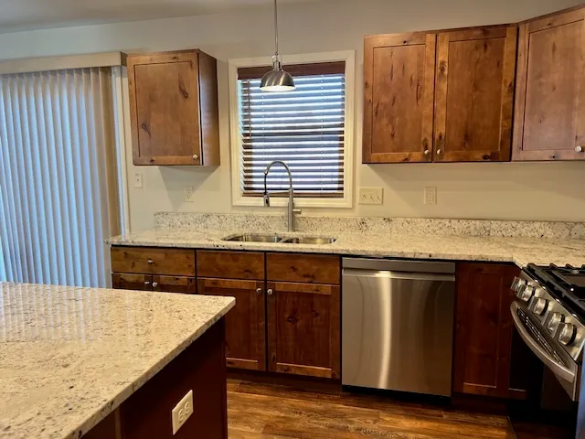 a kitchen with granite countertop wooden cabinets a sink and dishwasher