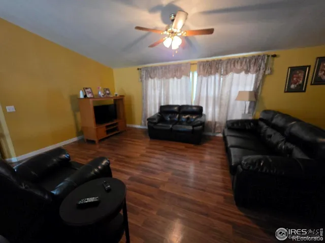 a living room with couches and kitchen view with wooden floor