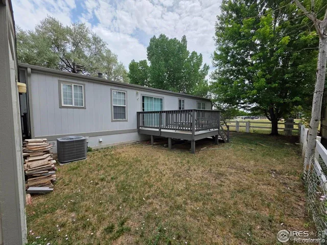 a view of a backyard with a small deck and wooden fence
