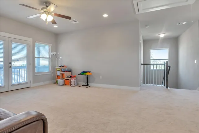 a view of an empty room with window and chandelier fan