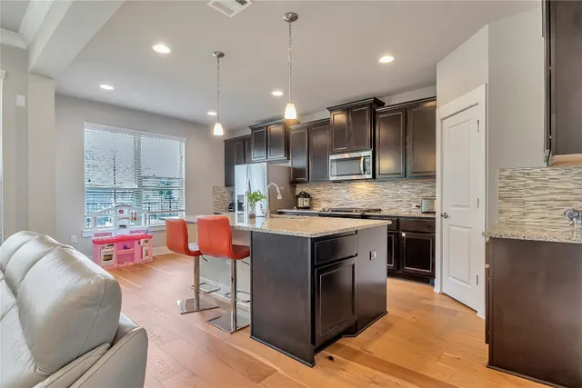 a kitchen with stainless steel appliances granite countertop a stove top oven a sink dishwasher and a refrigerator