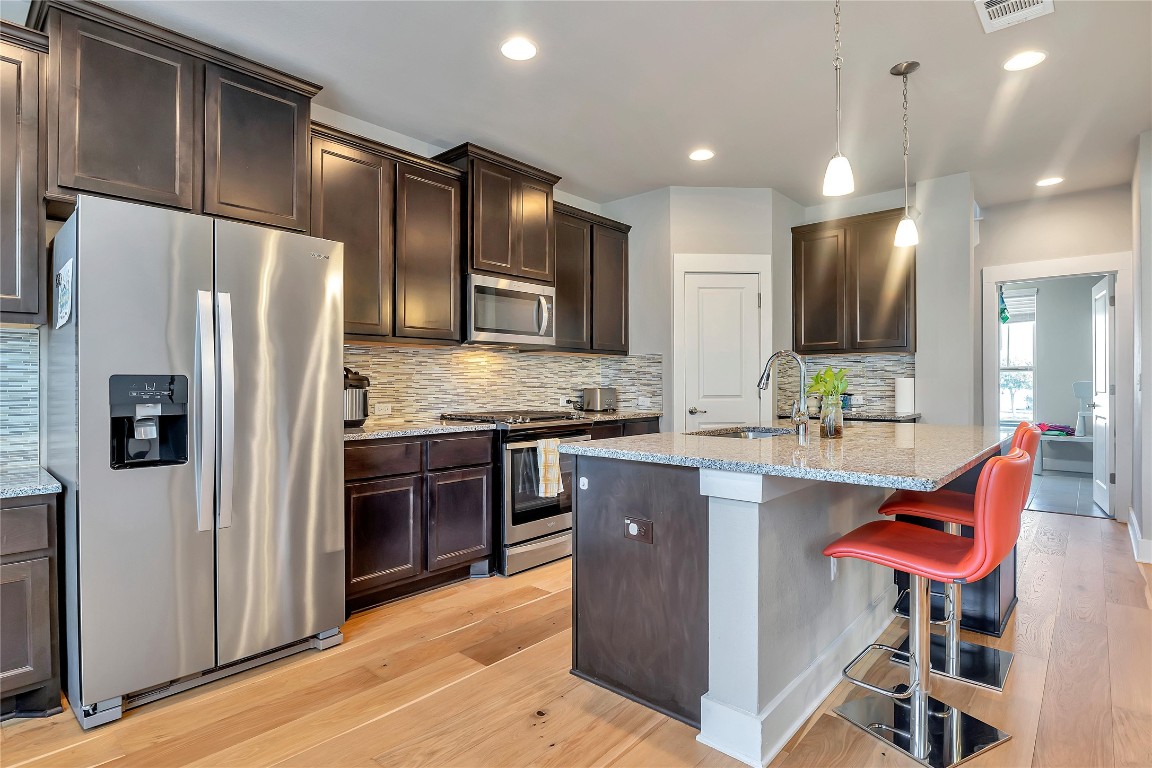 9302 McKnight Loop, Unit 43 Austin, TX 78717 - Photo 6 of 24 a kitchen with stainless steel appliances kitchen island granite countertop a refrigerator and a stove top oven