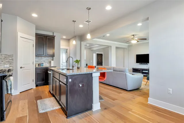 a kitchen with stainless steel appliances granite countertop a living room kitchen island a stove and a sink