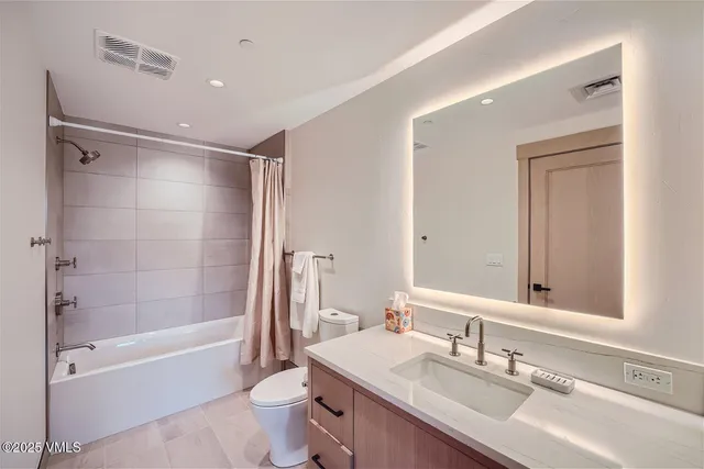 a bathroom with a bathtub shower sink mirror vanity and toilet