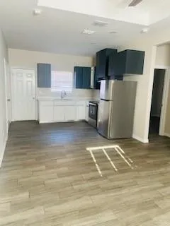 a view of kitchen with stainless steel appliances wooden floor and a refrigerator