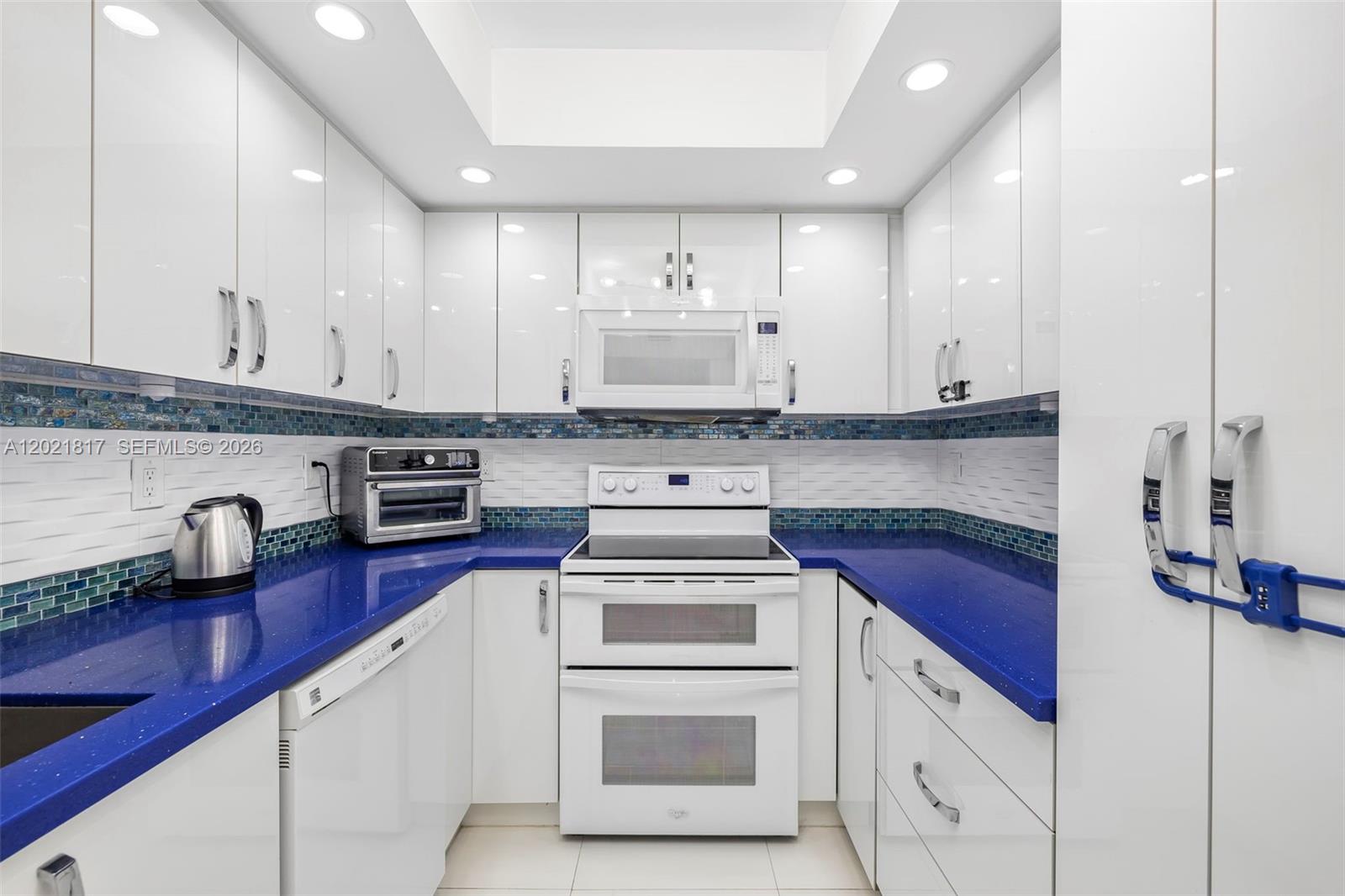 9511 Collins Avenue, Unit 1202 Surfside, FL 33154 - Photo 5 of 16 a kitchen with stainless steel appliances granite countertop a stove and white cabinets