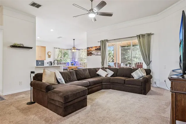 a living room with furniture a chandelier fan and a window