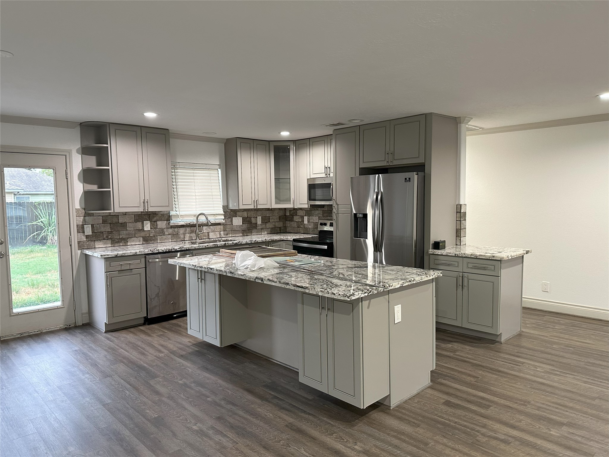 6646 Limestone Street Houston, TX 77092 - Photo 2 of 23 a kitchen with kitchen island granite countertop wooden floors stainless steel appliances a sink and a window