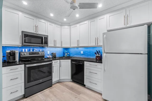 a kitchen with granite countertop white cabinets and stainless steel appliances