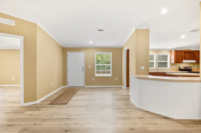 a view of a kitchen with kitchen island a sink wooden floor and living room view
