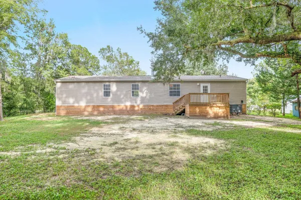 a backyard of a house with table and chairs and a large tree