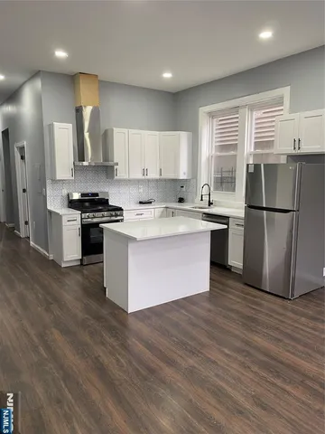 a kitchen with wooden floors and stainless steel appliances