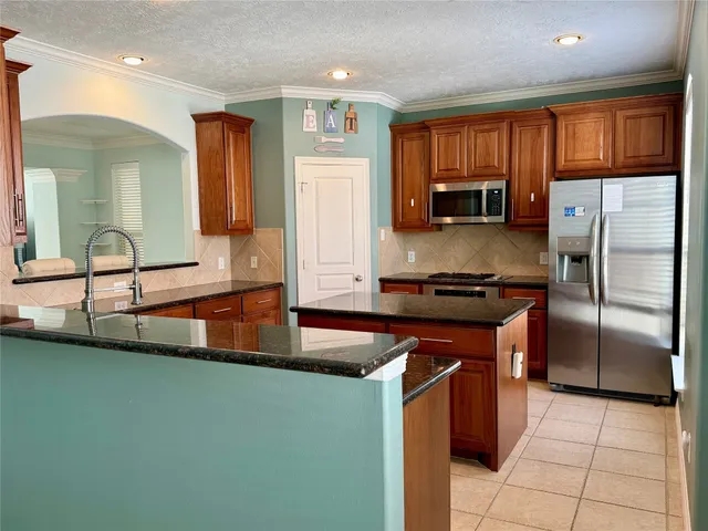a kitchen with kitchen island granite countertop a sink cabinets and stainless steel appliances