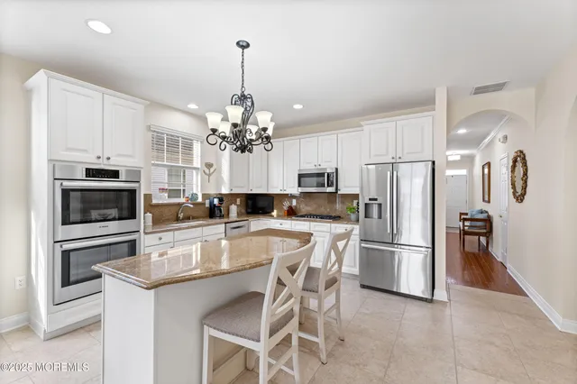 a kitchen with kitchen island granite countertop a center island a sink stainless steel appliances and cabinets