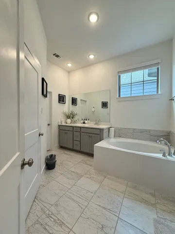 a bathroom with a tub sink and mirror