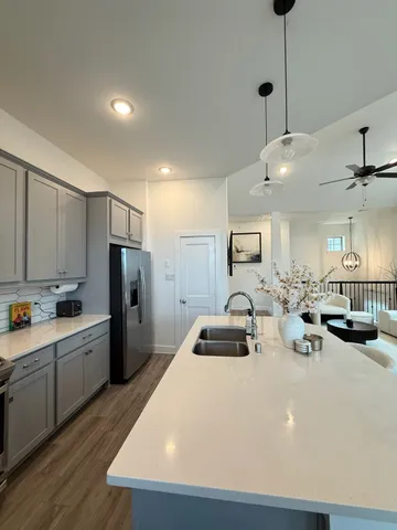 a kitchen with stainless steel appliances a refrigerator a sink a stove and white cabinets