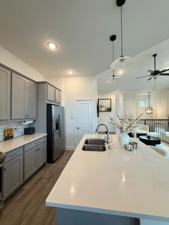 a kitchen with stainless steel appliances a refrigerator a sink a stove and white cabinets