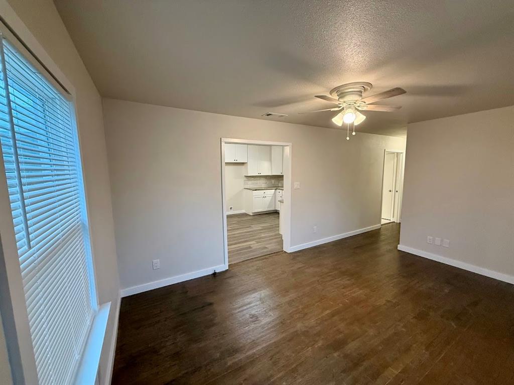 133 Gordon Drive Azle, TX 76020 - Photo 14 of 29 an empty room with wooden floor chandelier fan and windows