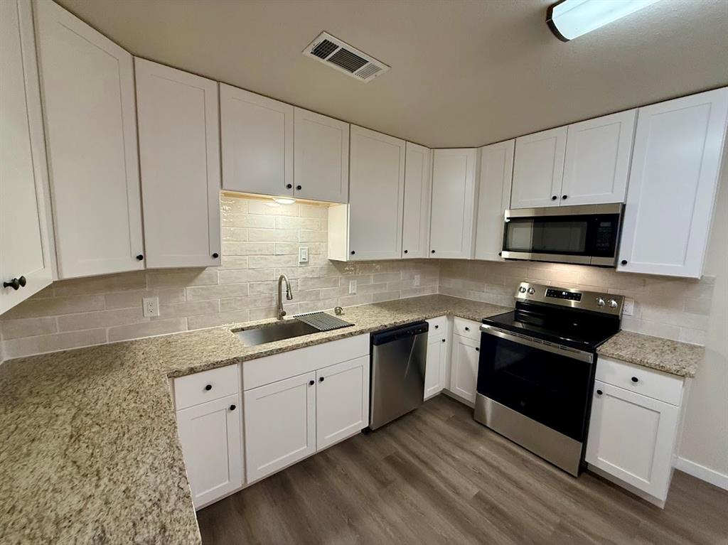 133 Gordon Drive Azle, TX 76020 - Photo 18 of 29 a kitchen with granite countertop white cabinets and stainless steel appliances