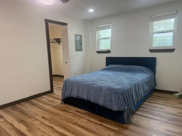a bedroom with a bed wooden floor and window